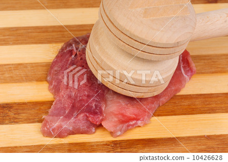 a wooden hammer for beating the meat and meat 10426628