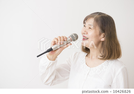 A woman in her 60's singing with a microphone A woman in her 60's singing with a microphone 10426826