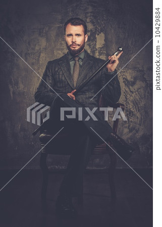 Handsome well-dressed with stick sitting in leather chair 10429884