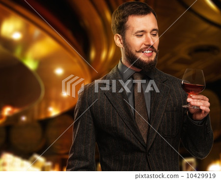 Handsome well-dressed man in jacket with glass of beverage in restaurant interior Handsome well-dressed man in jacket with glass of beverage in restaurant interior 10429919