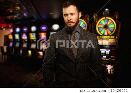 Handsome well-dressed man against slot machines in a casino Handsome well-dressed man against slot machines in a casino 10429921