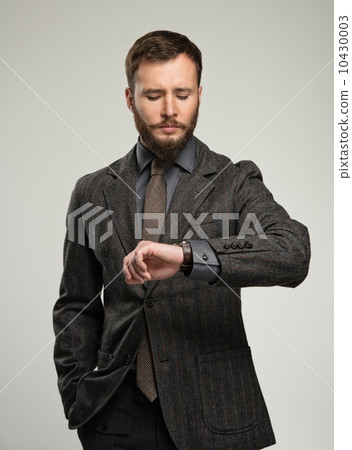 Handsome well-dressed man with beard looking at his wrist watch Handsome well-dressed man with beard looking at his wrist watch 10430003