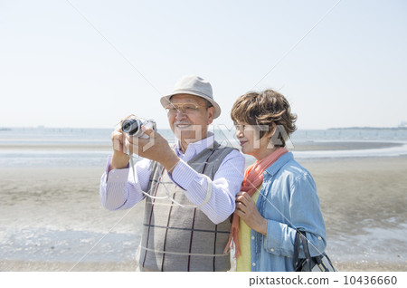 Senior couple taking photos at the beach 10436660