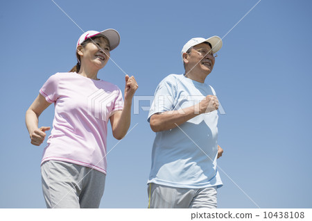 A couple in their 60s jogging at the beach 10438108