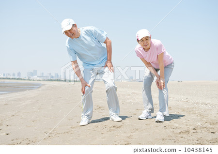 一對60多歲的夫婦跪在沙灘上 一對60多歲的夫婦跪在沙灘上 10438145