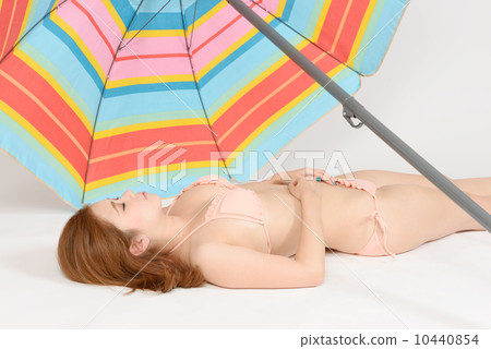 游泳衣的一位小姐在沙灘傘下 10440854