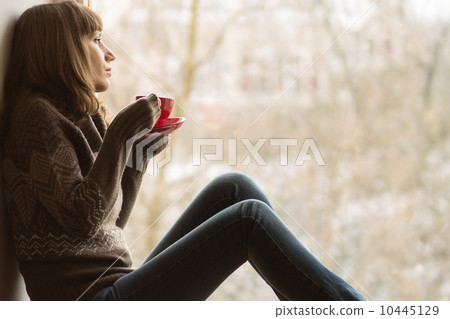 Beautiful girl dreaming with cup of coffee or tea near window Beautiful girl dreaming with cup of coffee or tea near window 10445129