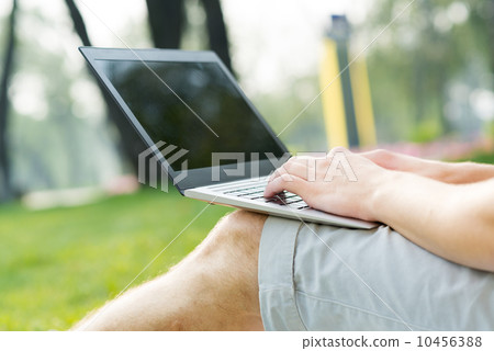 young man working in the park with a laptop young man working in the park with a laptop 10456388
