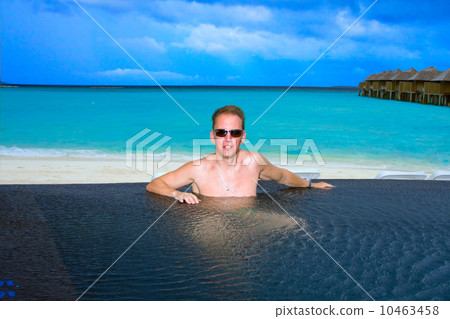 Young sports man in the pool and ocean in the background. Maldives. 10463458