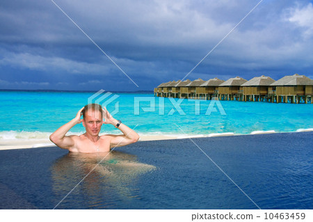 Young sports man in the pool and ocean in the background. 10463459