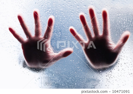 Silhouettes of two right hands behind wet glass 10471091