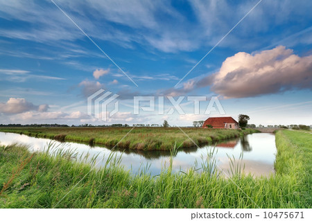charming farmhouse by river over blue sky 10475671