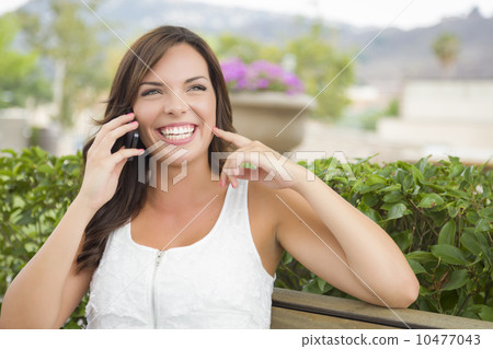 Young Adult Female Talking on Cell Phone Outdoors on Bench Young Adult Female Talking on Cell Phone Outdoors on Bench 10477043