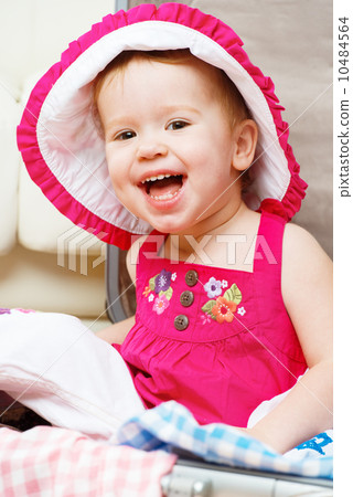 happy baby girl is going on trip, pack suitcase 10484564