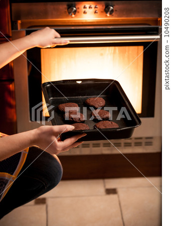 photo of housewife putting pan with cookies in oven photo of housewife putting pan with cookies in oven 10490208