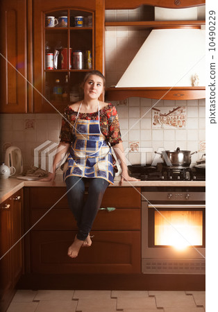 housewife sitting on tabletop near working oven housewife sitting on tabletop near working oven 10490229