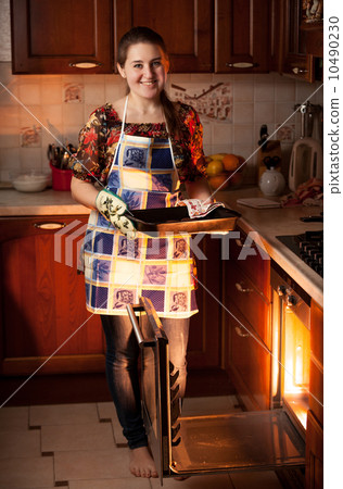 housewife holding form with chocolate cookies near oven housewife holding form with chocolate cookies near oven 10490230