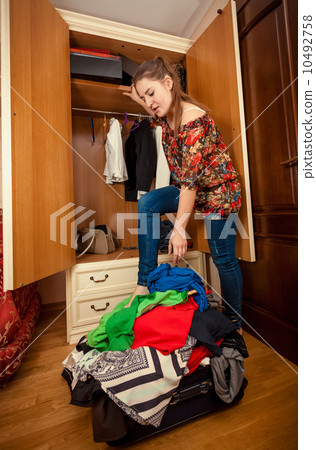 brunette woman packing clothes in big suitcase 10492758