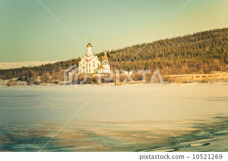 Christian Orthodox Church temple on icy lake with forest mountains on background Beautiful Landscape 10521269