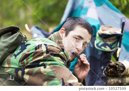 Young recruit with harmonica and rifle in forest 10527509