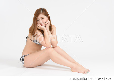 穿著坐和麵頰的泳裝的一名婦女 穿著坐和麵頰的泳裝的一名婦女 10531696