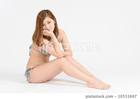 穿著坐和麵頰的泳裝的一名婦女 穿著坐和麵頰的泳裝的一名婦女 10531697