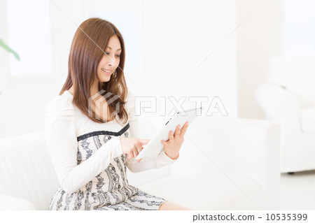 觀看一種片劑的婦女在屋子裡 觀看一種片劑的婦女在屋子裡 10535399
