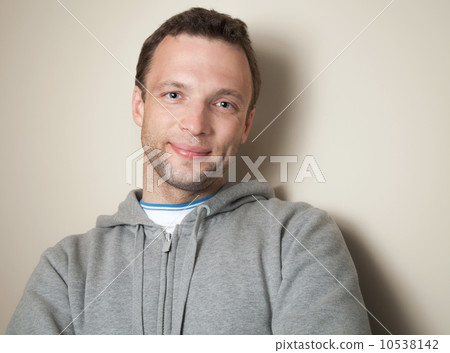 Young positive Caucasian man in gray sports jacket with hood 10538142