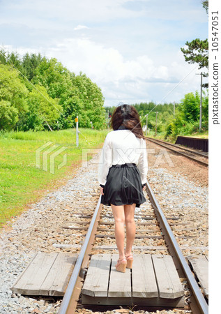 A young woman standing at a railroad crossing 10547051