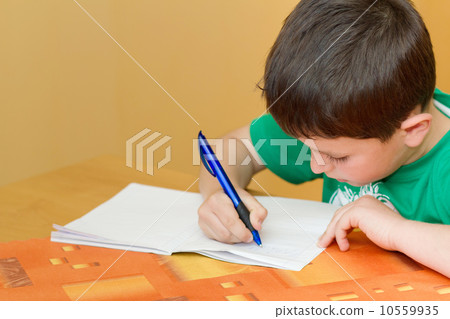 school boy writting homework in workbook 10559935