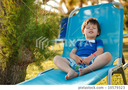 Cute toddler boy sitting on a sunbed Cute toddler boy sitting on a sunbed 10579323