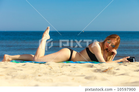 Summer vacation Girl with phone tanning on beach Summer vacation Girl with phone tanning on beach 10597900