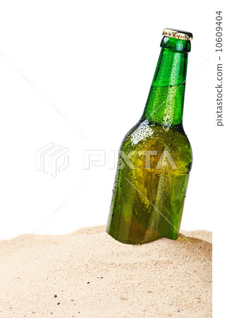 Beer bottle on a sandy beach isolated 10609404
