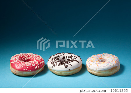 three donuts with color icing isolated on blue background with c 10611265