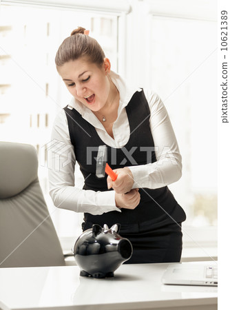 angry businesswoman breaking piggy bank with hammer angry businesswoman breaking piggy bank with hammer 10621389