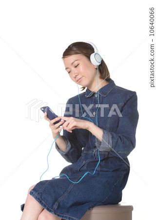 A woman listening to music on a smartphone A woman listening to music on a smartphone 10640066