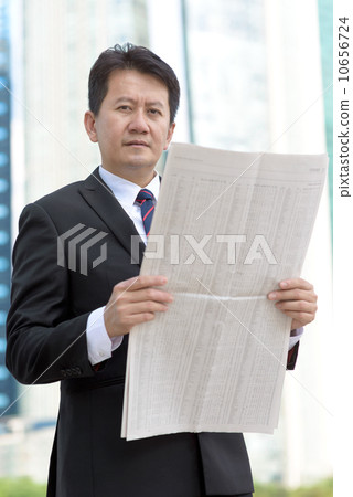 Successful entrepreneur stock agent business man reading newspaper in front of glass office building 10656724