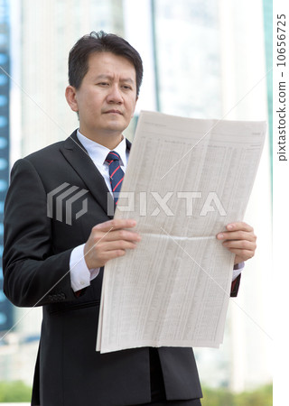 Successful entrepreneur stock agent business man reading newspaper in front of glass office building 10656725