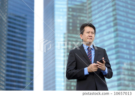 Successful entrepreneur business man using mobile phone in front of glass office building 10657013