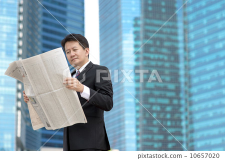 Successful entrepreneur stock agent business man reading newspaper in front of glass office building 10657020