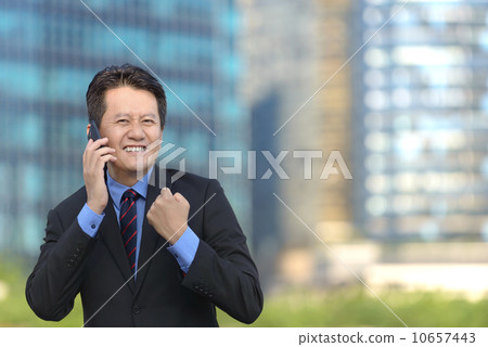 Successful entrepreneur business man hearing good news in front of glass office building 10657443