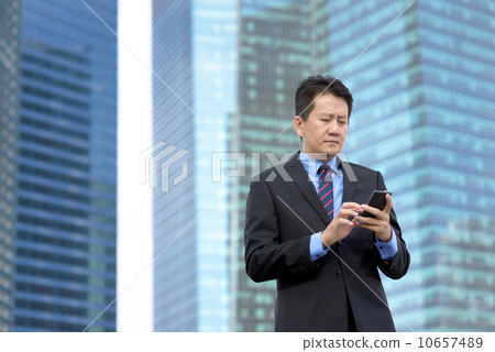 Successful entrepreneur business man using mobile phone in front of glass office building 10657489