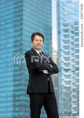 Successful entrepreneur business man standing in front of glass office building folding arms 10657490