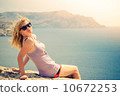 Young Woman blonde hair relaxing outdoor on seaside rocky cliff Lifestyle and Summer vacations 10672253