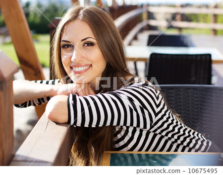 Young woman drinking coffee in a cafe outdoors 10675495