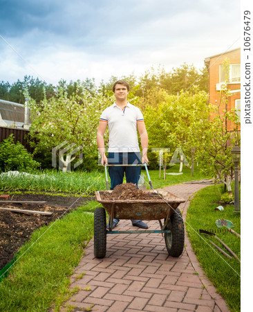 man carrying wheelbarrow at beautiful garden man carrying wheelbarrow at beautiful garden 10676479