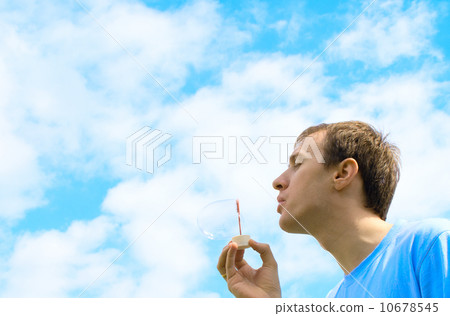 The young man starts up soap bubbles against the blue sky 10678545