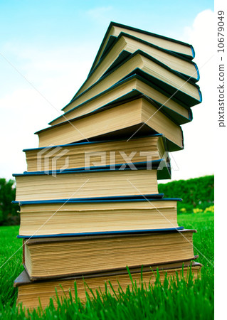 A stack of books lying on green grass A stack of books lying on green grass 10679049