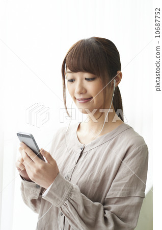 A woman listening to music on a smartphone 10687752