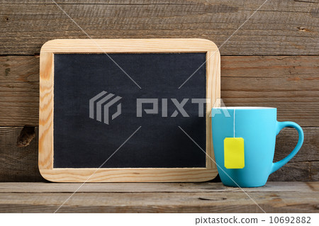 Cup of tea and small blackboard on old wooden background 10692882